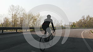 Confident triathlete riding bicycle. Triathlon training. Follow shot of cyclist pedaling on bicycle. Slow motion