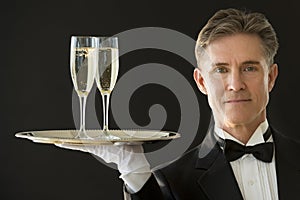 Confident Waiter Carrying Serving Tray With Champagne Flutes