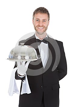 Confident waiter holding domed tray