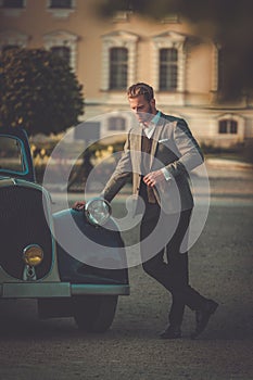 Confident wealthy man near classic convertible