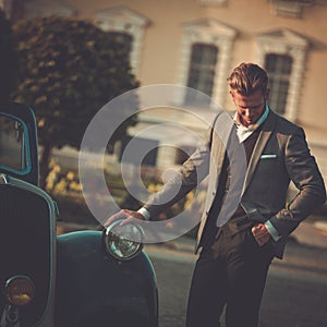 Confident wealthy man near classic convertible