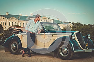 Confident wealthy man near classic convertible