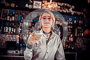 Confident woman barman formulates a cocktail in cocktail bars