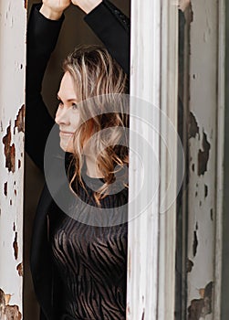 a, confident woman in a black suit at the old window