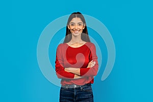 Confident Woman With Crossed Arms Standing Against Blue Background