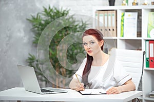 Confident woman doctor sitting at the table in her office and smiling at camera. healthcare concept