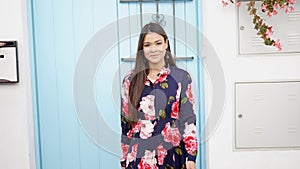 Confident Woman in Floral Dress Standing by Blue Door