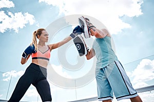 Confident woman is hitting man during training outdoors