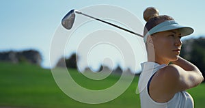 Confident woman playing golf on fairway. Golfer swinging ball at country club.