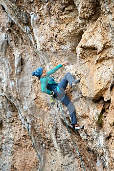 confident woman rock climber climbing on cliff, resting and griping hold