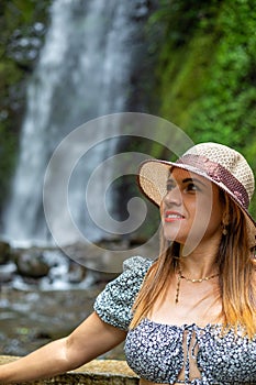 a woman is standing by a waterfall and looking over her shoulder
