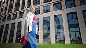 Confident woman strolling at business center smiling looking around in slow motion. Bottom angle portrait of successful