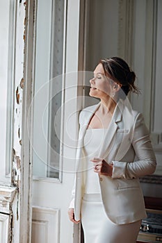 a, confident woman in a white suit at the old window. image of bride
