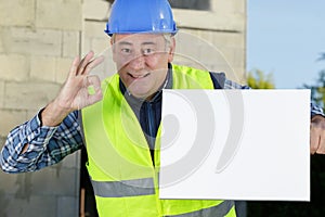 confident worker presenting empty board and making ok sing