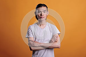 Confident young adult asian man standing with arms crossed