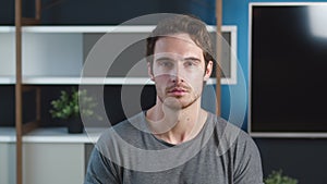 Confident young adult european man looking at camera standing at home. Close up portrait of millennial male young