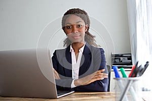 Confident young african american businesswoman in suit sitting at office desk