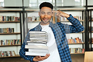 Confident young african male student holding stack of books