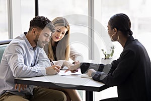 Confident young African realtor pointing at paper agreement for customers