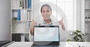 Confident young Asia female doctor in white medical uniform with stethoscope looking at camera and showing laptop computer in