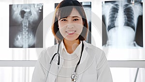 Confident young Asia female doctor in white medical uniform with stethoscope looking at camera and smiling while video conference