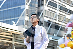 Confident young Asian business man in suit standing and looking at far away at outside office