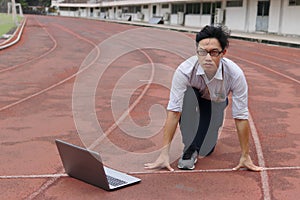 Confident young Asian businessman with laptop ready start position to forward on race track. business vision concept.