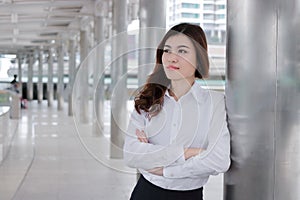 Confident young Asian busineswoman leaning a pole at walkway outside office. Leader business woman concept.