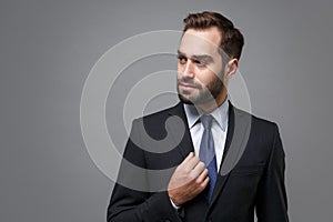 Confident young bearded business man in classic black suit shirt tie posing isolated on grey background studio portrait