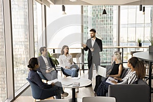 Confident young business leader man talking to diverse group