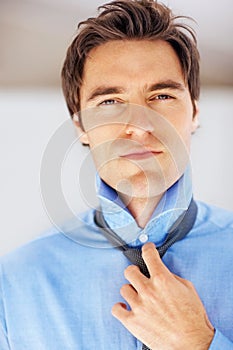 Confident young business man getting dressed for a meeting. Portrait of a confident young executive getting dressed for