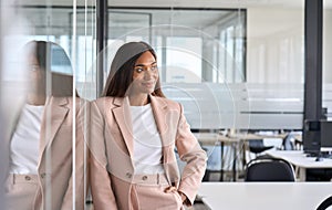 Confident young business woman standing in office looking away, portrait.