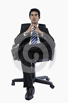 Confident young businessman seated in an office chair. Conceptual image