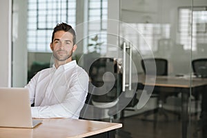 Confident young businessman sitting at his office desk