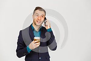 Confident young businessman using cell phone and drinking coffee