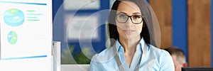 Confident young businesswoman in corporation office, wearing glasses