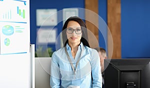 Confident young businesswoman in corporation office, wearing glasses