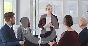 Confident young businesswoman giving presentation to team in office.