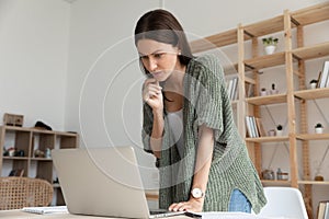 Confident young businesswoman holding chin thinking about project.