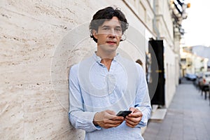 Confident young casual man holding mobile phone