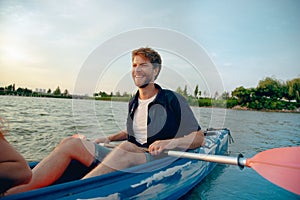 Fiducioso giovane uomo kayak sul un fiume tramonto sul 