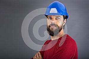 Confident young construction worker with hardhat and arms folded