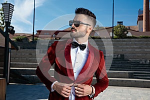 Confident young elegant man arranging coat outdoor