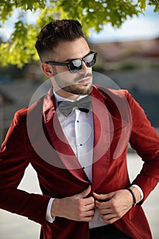 Confident young elegant man arranging red velvet tuxedo