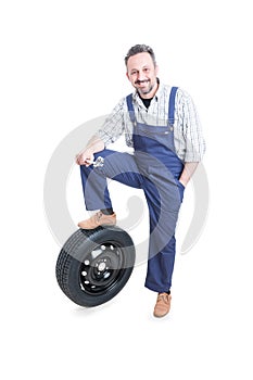Confident young engineer standing near car wheel