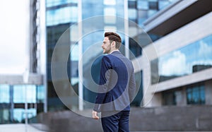 Confident young enterpreneur going to office building at city center