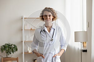 Confident young female physician standing in medical office interior, portrait
