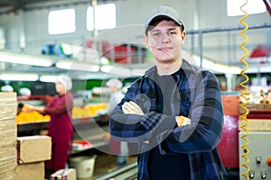 Young foreman of fruit factory standing on citrus sorting line