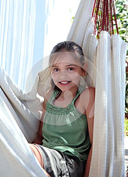 Confident young girl sitting in hammock on vacation