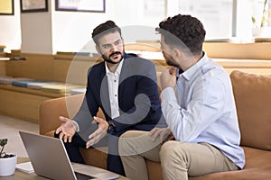 Confident young Indian business man presenting project on laptop